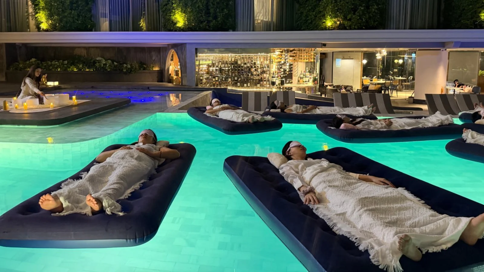 Guests enjoying a floating sound bath in a private pool at night