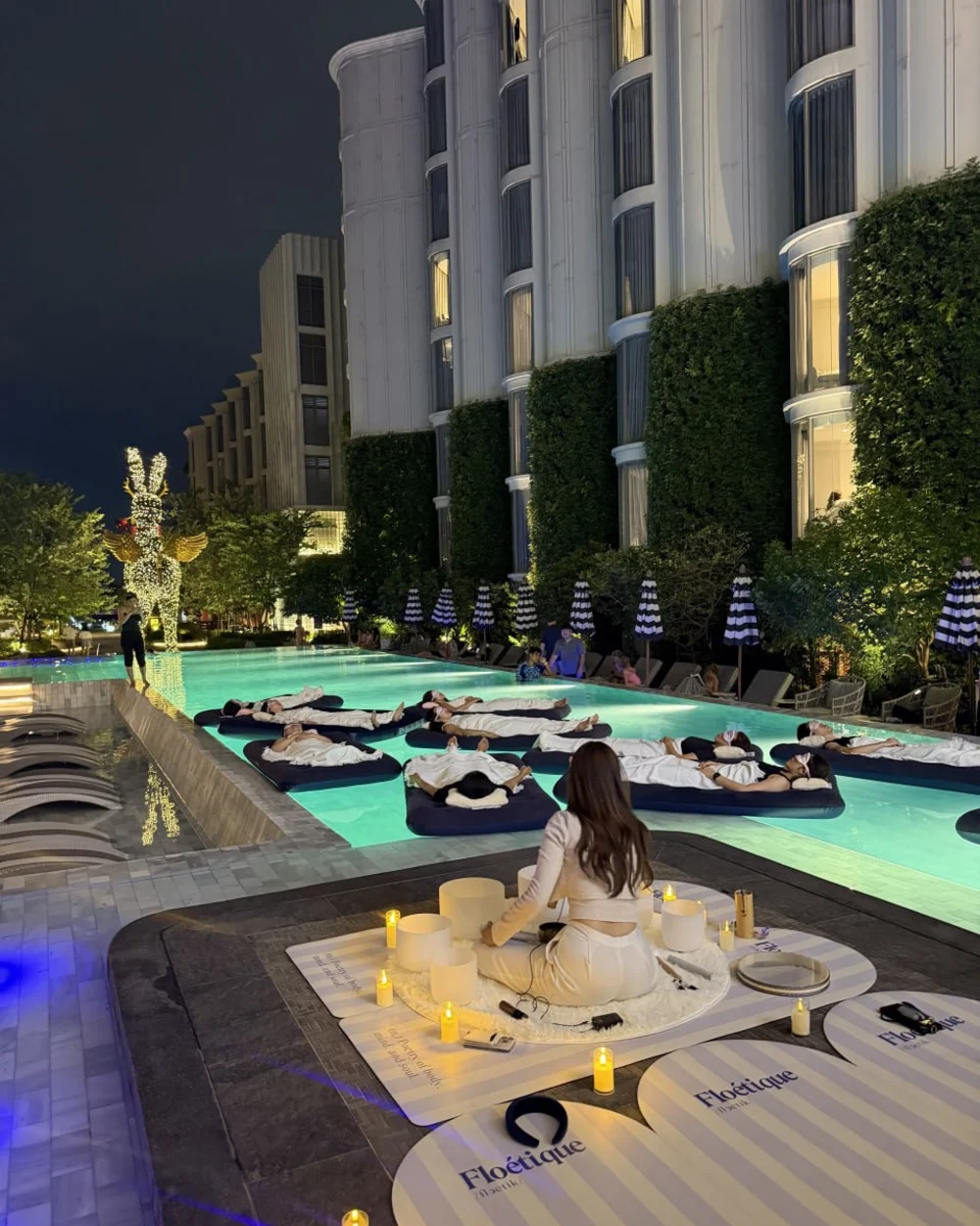 Nighttime floating sound bath with a facilitator and guests in a private pool